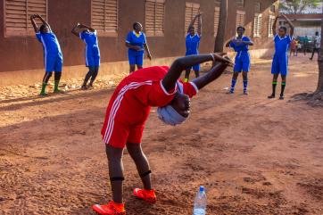 Malian women stretch and warm up prior to playing soccer.