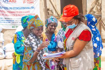 Malian receives voucher from mercy corps employee.