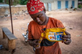 Participant pours oil into smaller container during Justice and Stability program in the Sahel