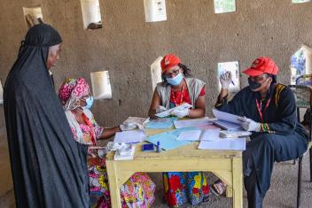 L'équipe du projet - assise et masquée - avec un bénéficiaire sur le site de distribution à Djenné.
